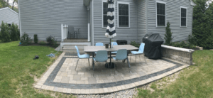 Rectangular patio made with concrete pavers with a table and six chairs on top of it